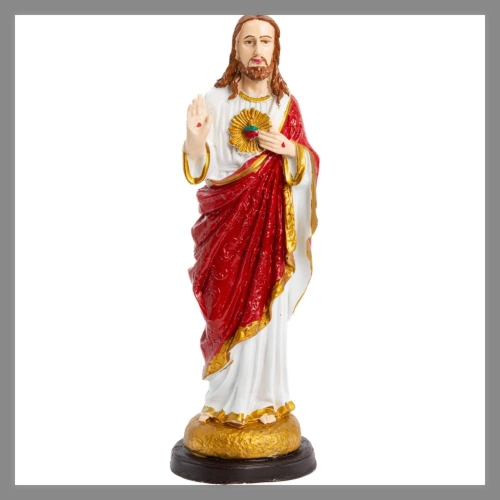 Een beeld van Jezus Christus gekleed in een witte tuniek met een rode mantel, met een gouden basis.
